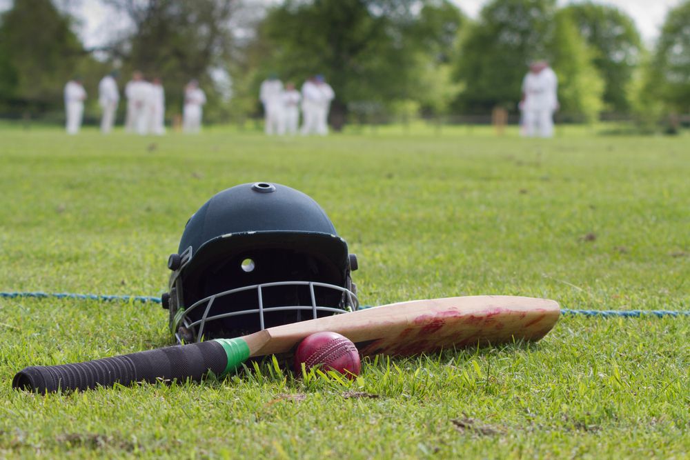 cricket bat, ball and helmet laying on the grass