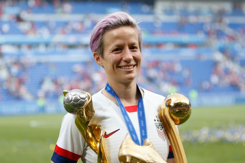 Megan Rapinoe holding trophies